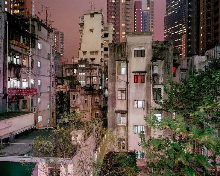 This may contain: the city skyline is lit up at night with buildings in the foreground and trees on the other side