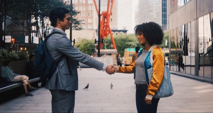 This may contain: a man and woman shaking hands on the sidewalk