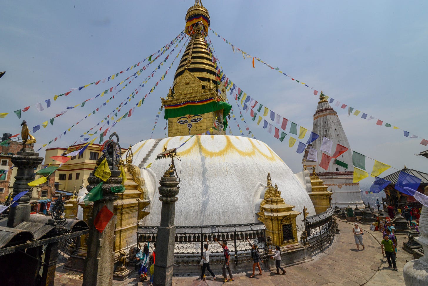 https://upload.wikimedia.org/wikipedia/commons/b/bc/Pilgrims_circumambulating_the_stupa_clockwise_whilst_spinning_its_prayer_wheels_-_Swayambhunath_%2817228237094%29.jpg