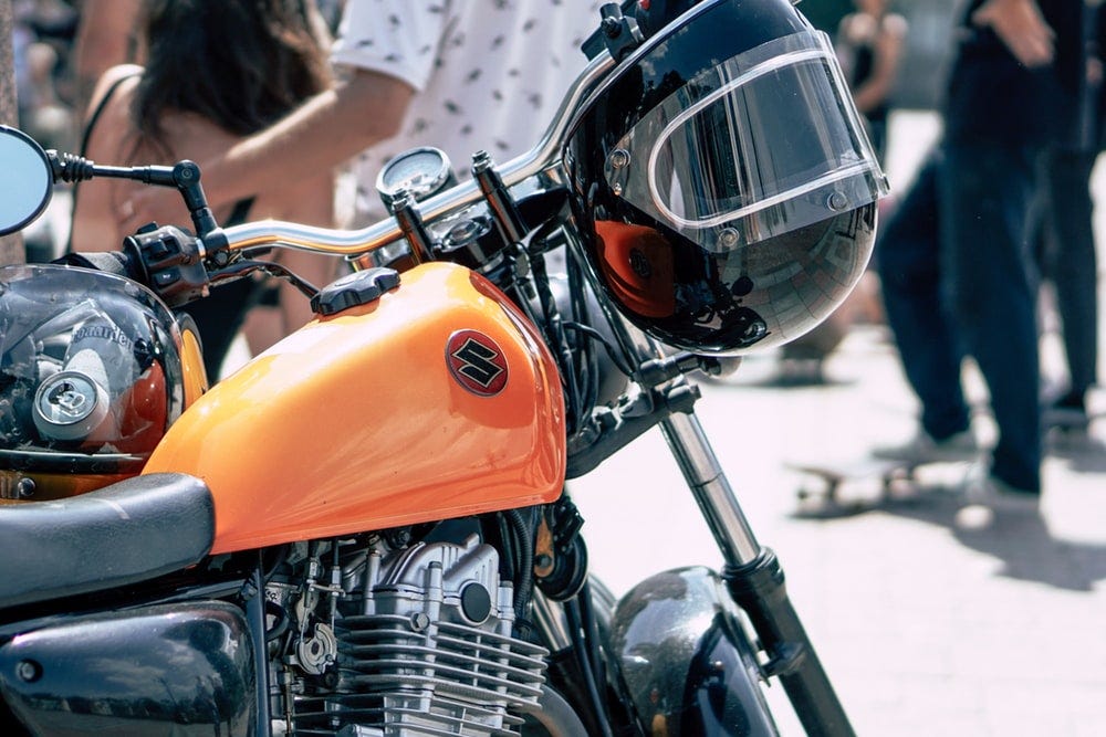black helmet hanging on black and orange Suzuki motorcycle