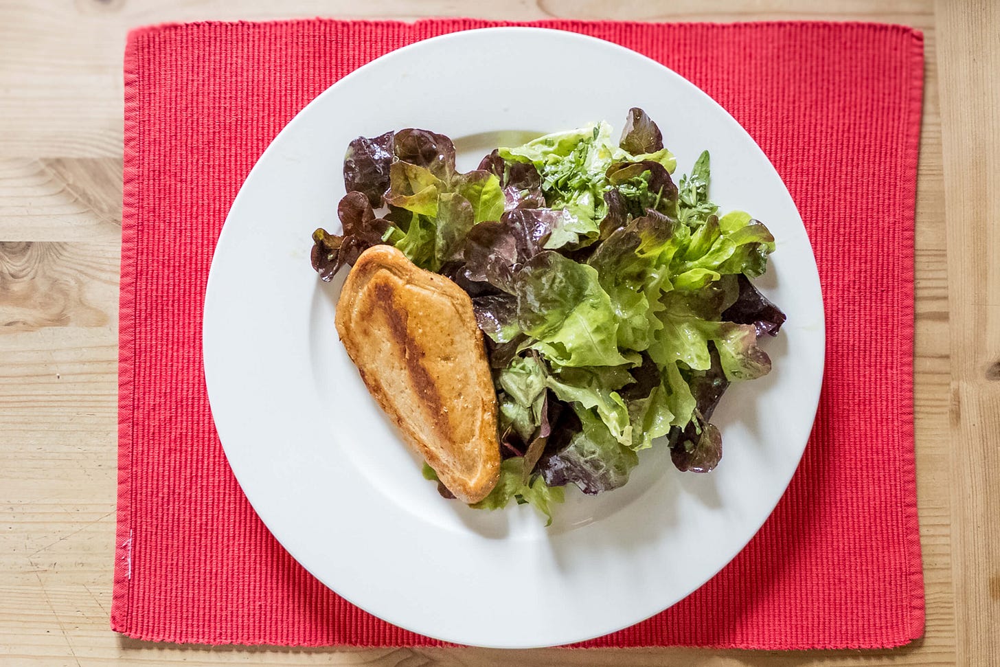Ein goldbraun angebratenes «My Vay Gourmet-Filet» aus Pilzprotein liegt neben einem frischen grünen Blattsalat auf einem weissen Teller, der auf einer roten Platzmatte steht. Ein goldbraun angebratenes «My Vay Gourmet-Filet» aus Pilzprotein liegt neben einem frischen grünen Blattsalat auf einem weissen Teller, der auf einer roten Platzmatte steht.