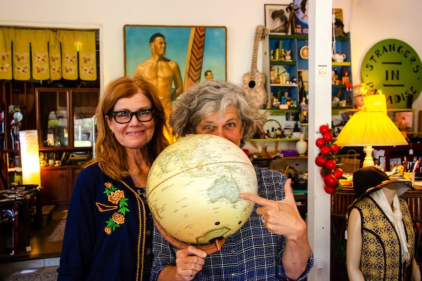 Two women hold up a globe and point at the east coast of Australia. Two women hold up a globe and point at the east coast of Australia.