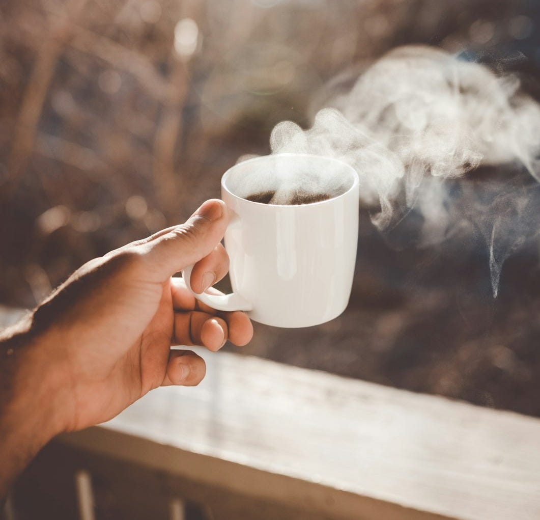 person holding white ceramic cup with hot coffee