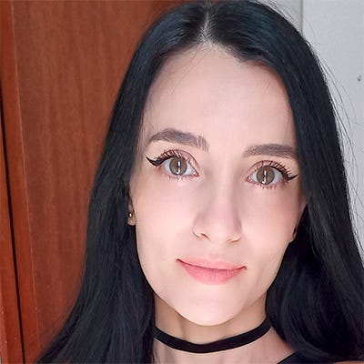 A imagem mostra uma mulher enquadrada dos ombros para cima, olhando diretamente para a câmera. Ela tem cabelos longos e escuros e veste uma blusa de cor clara. O fundo é neutro e pouco detalhado, mantendo o foco no rosto da pesquisadora. A imagem mostra uma mulher enquadrada dos ombros para cima, olhando diretamente para a câmera. Ela tem cabelos longos e escuros e veste uma blusa de cor clara. O fundo é neutro e pouco detalhado, mantendo o foco no rosto da pesquisadora.