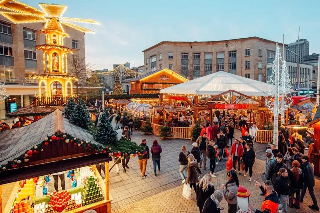 Bristol Christmas Market in Broadmead showing festive wooden chalets, German pyramid tower, and crowds of shoppers before surrounding demolition projects begin 2025 Bristol Christmas Market in Broadmead showing festive wooden chalets, German pyramid tower, and crowds of shoppers before surrounding demolition projects begin 2025