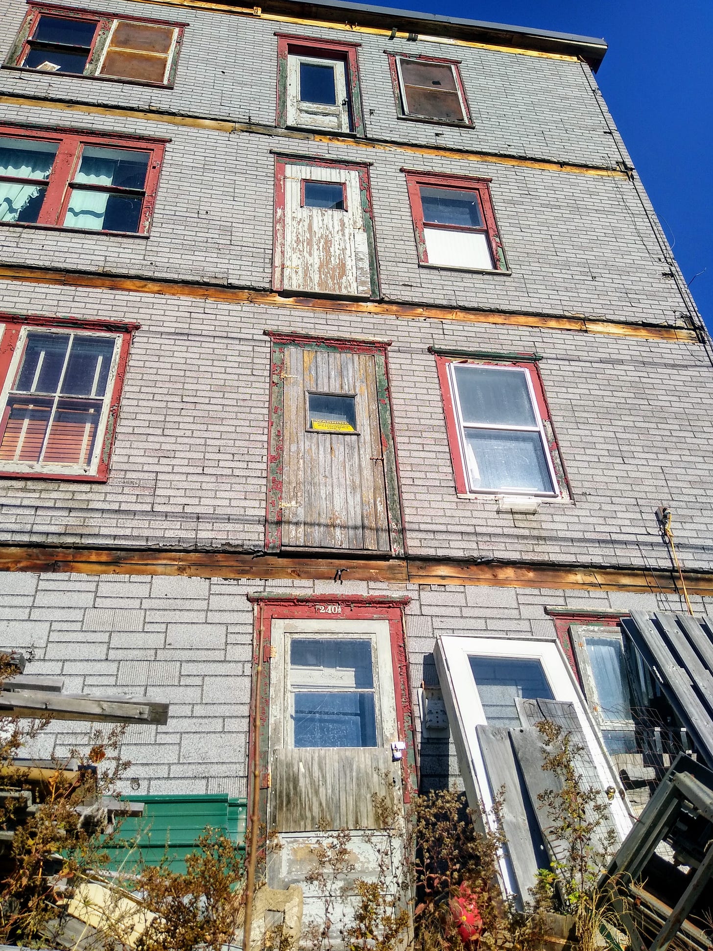A small brick apartment building now missing stairs with doors that go nowhere. 