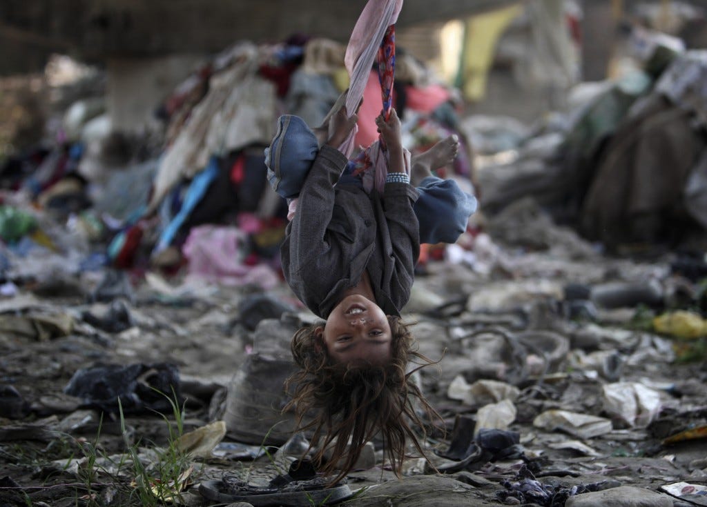 A child living in a slum plays on a swing under a bridge on the bank of Bagmati River in Kathmandu October 17, 2011. Photo by Navesh Chitrakar/Reuters