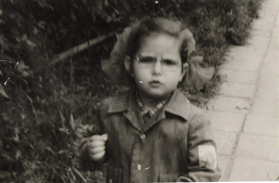 A girl wearing glasses and a very serious facial expression is taking a break from sniffing a petal to look at the camera A girl wearing glasses and a very serious facial expression is taking a break from sniffing a petal to look at the camera
