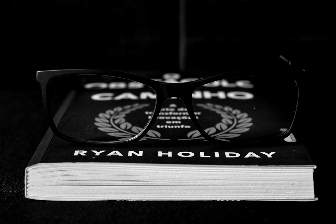 Glasses resting on a blue book by ryan holiday. Glasses resting on a blue book by ryan holiday.
