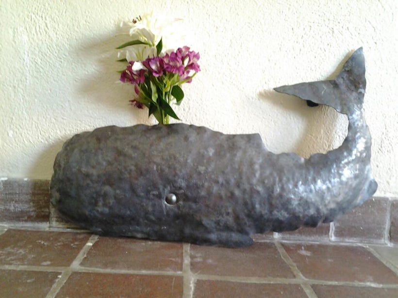 A forged steel whale with a spray of flowers coming from behind where the blowhole would be