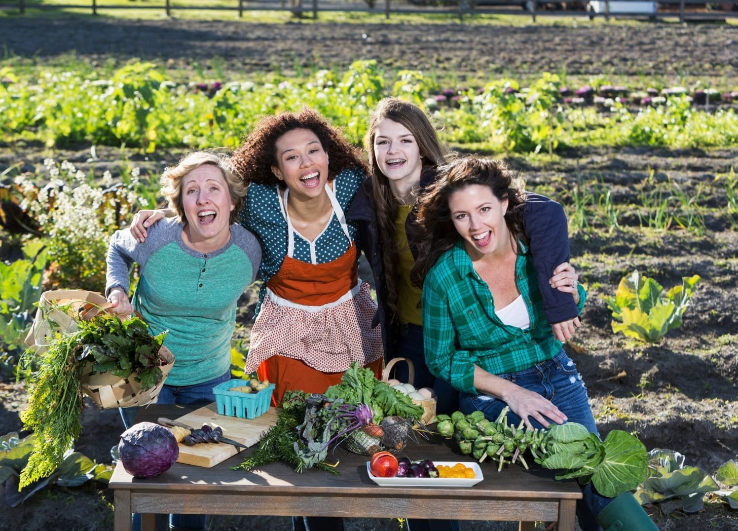 A group of smiling local farmers holding fresh produce, showing how partnerships strengthen communities and guest experiences.