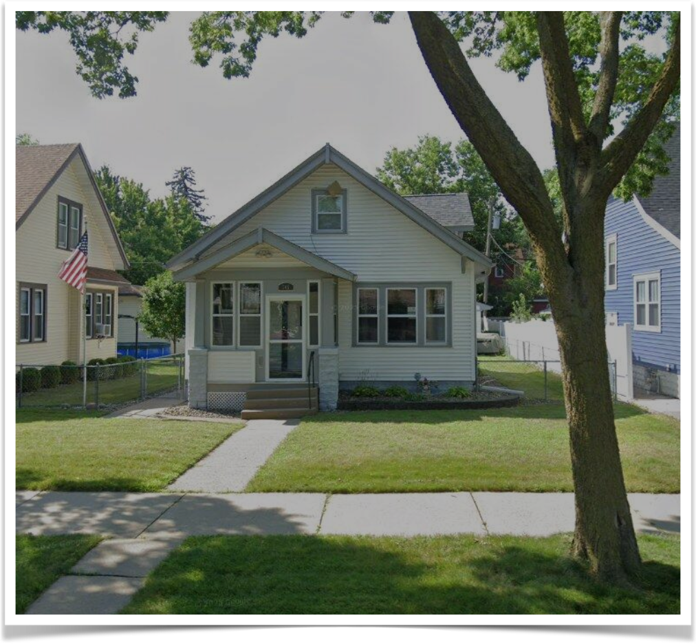 Small bungalow style home, white with green trim and a green trimmed yard. Small bungalow style home, white with green trim and a green trimmed yard.