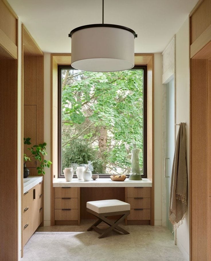 This may contain: a bathroom with a large window next to a sink and counter top under a light fixture