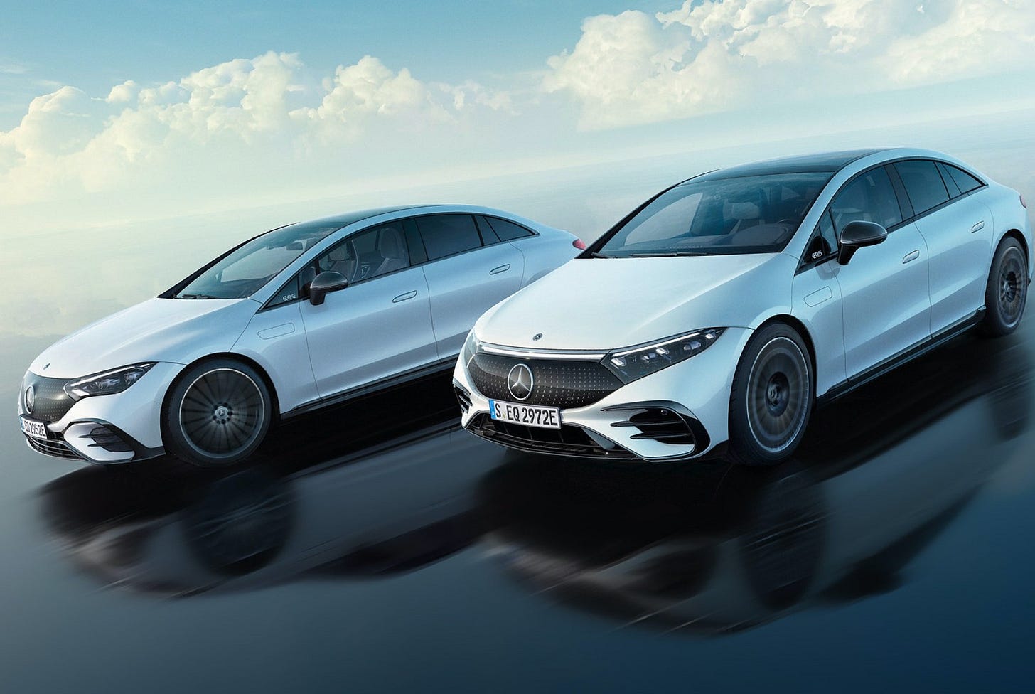 A Mercedes-EQ EQE and Mercedes-EQ EQS on a beach. Wet sand is reflecting the cars and horizon.