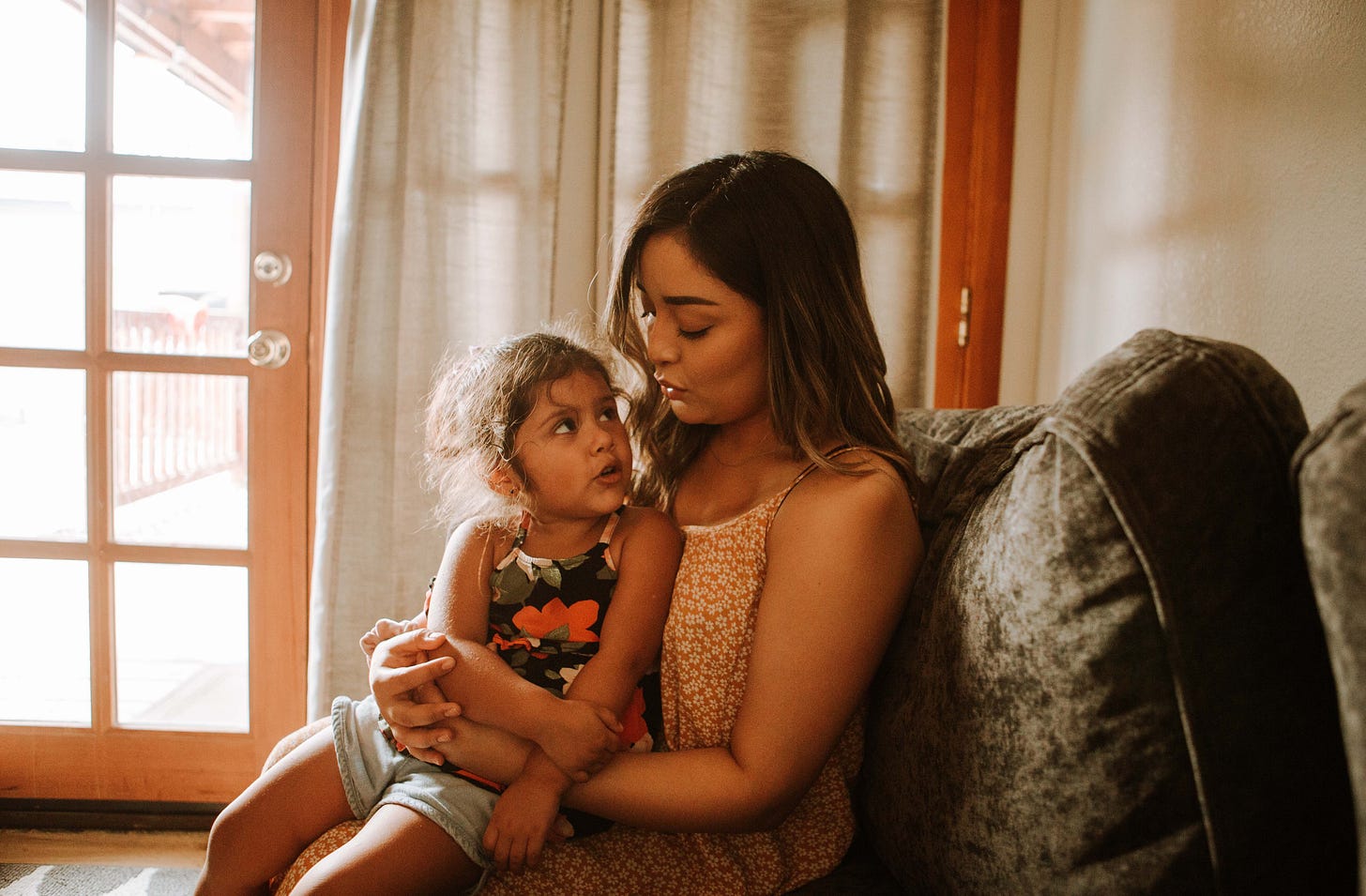 Mother with child on her lap, sitting a comfy chair.