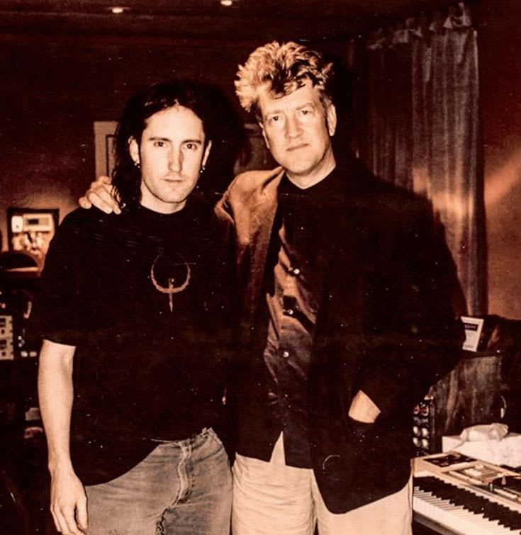 This may contain: two men standing next to each other in front of a keyboard