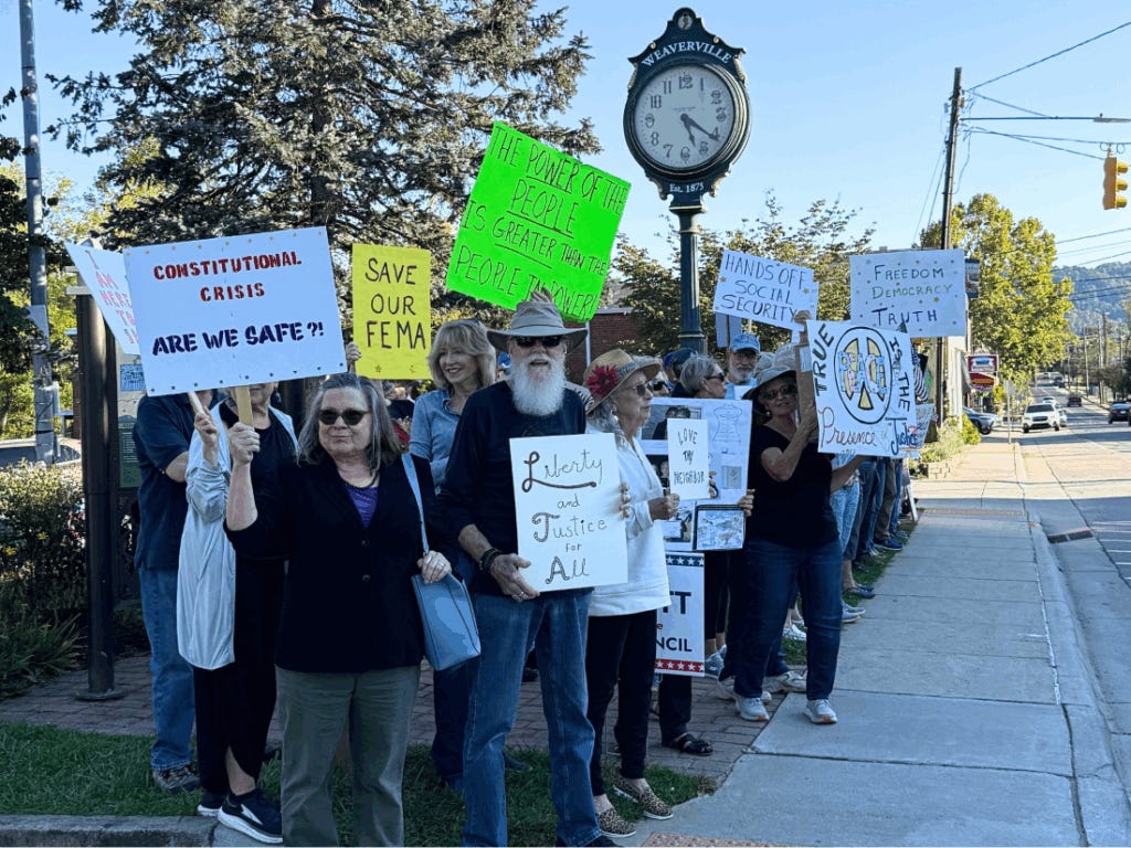 Demonstrators hold up signs in front of the Weaverville clock