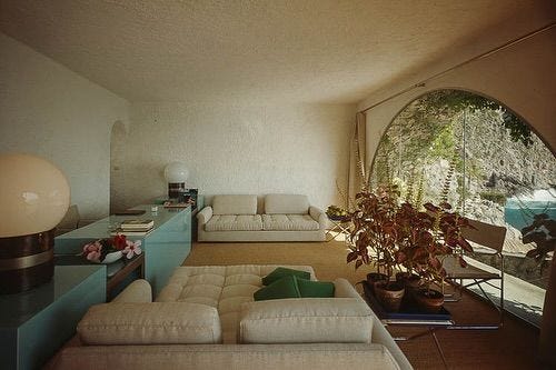 This may contain: a living room filled with furniture and a large window in the wall next to it