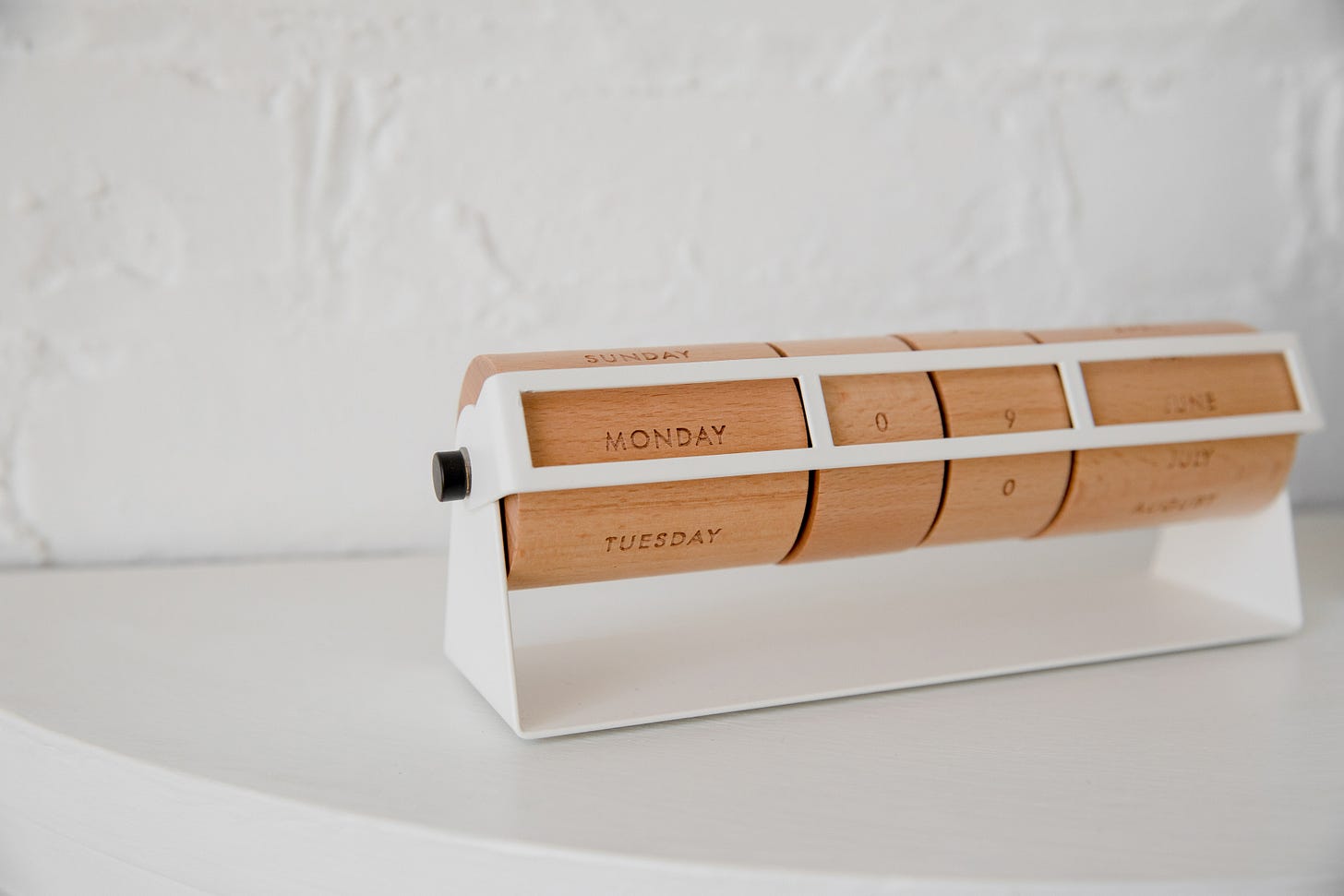 perpetual desk calendar with wooden wheels for Day of the week, date and month sitting on a white table