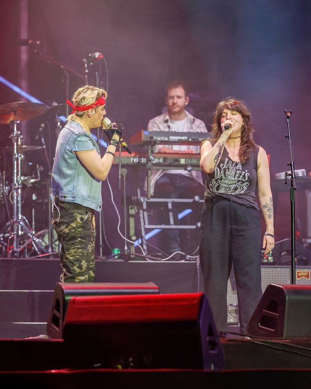 Megan Falley and Brandi Carlile on stage, signing to each other with microphones in hand.