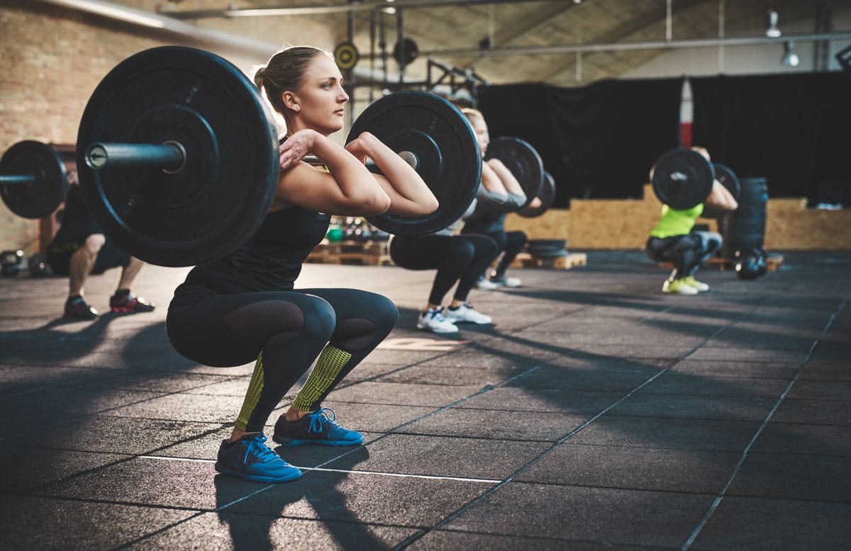 Group of women doing weighted squats in a gym.
