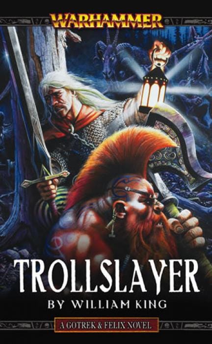The cover of "Trollslayer," with Geoff Taylor art depicting a terrified, torch-clutching Felix and axe-wielding Gotrek preparing to battle goat-headed Beastmen. The text reads: "Trollslayer: By William King." The line after the title says "A Gotrek & Felix Novel."