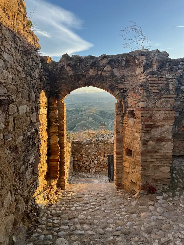 Stone archway in the Ghost Town of Craco with hills of Basilicata visible through it