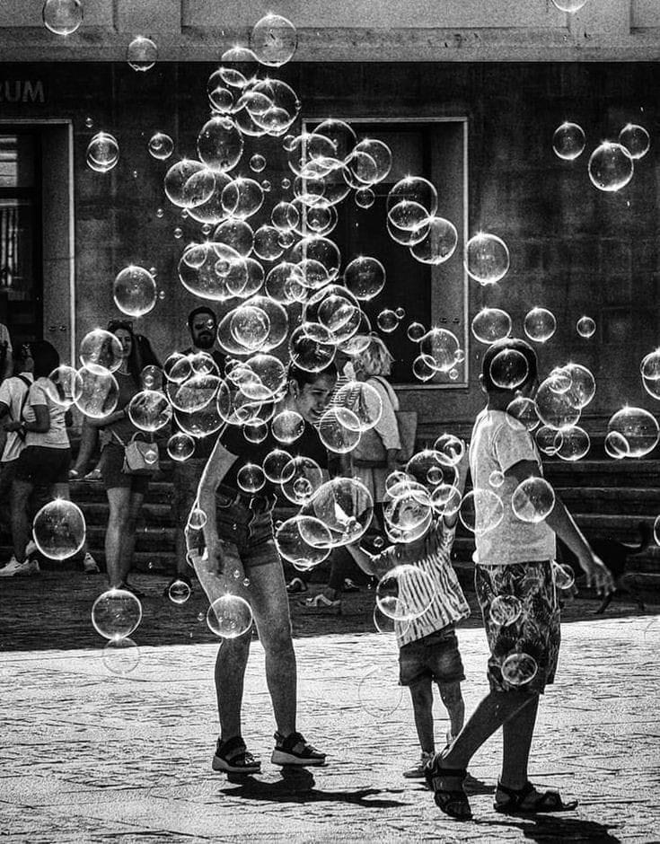 This may contain: two children are playing with soap bubbles in front of a building