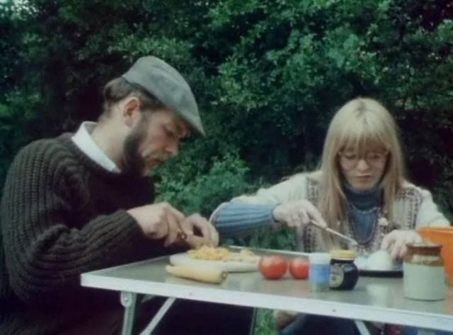 Couple chopping vegetables at a camping table on a campsite Couple chopping vegetables at a camping table on a campsite