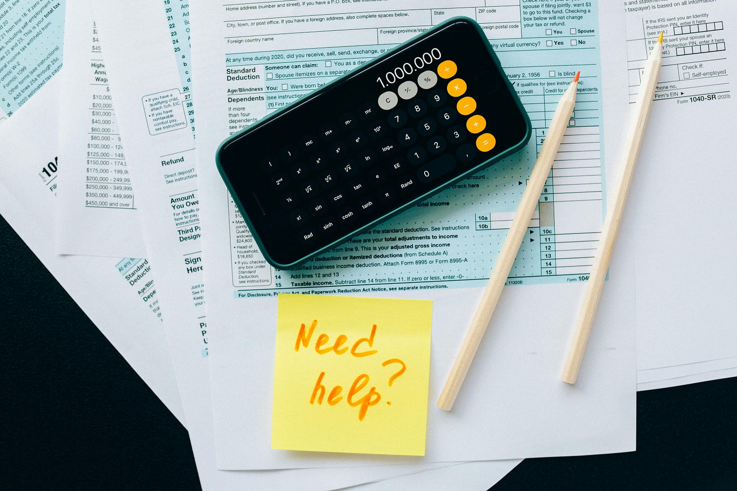 Financial planning concept with calculator displaying one million, tax documents, and a sticky note reading “Need help?”. Financial planning concept with calculator displaying one million, tax documents, and a sticky note reading “Need help?”.