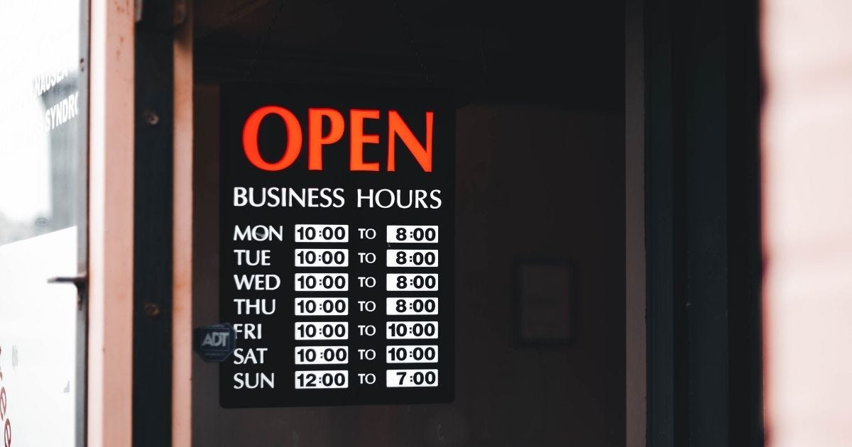 Close-up of an open business hours sign displayed in a  window