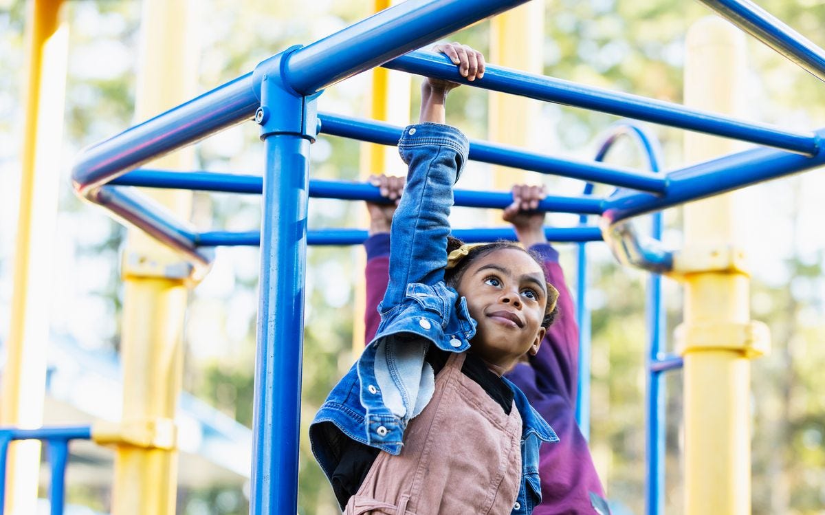 girl playing on playground monkey bars