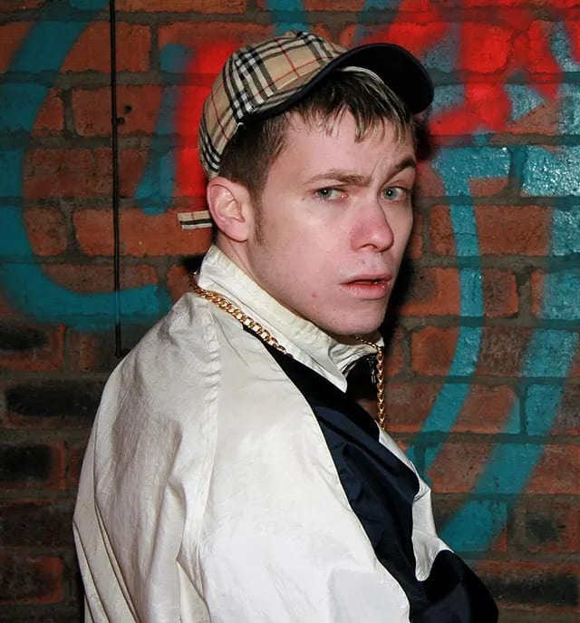 A quintessential British 'Chav' look: branded tracksuit and a baseball cap, a notable subculture style of the 2000s. A quintessential British 'Chav' look: branded tracksuit and a baseball cap, a notable subculture style of the 2000s.