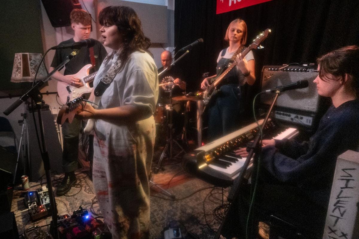 A photo of five-piece band Posturing, mid-performance.