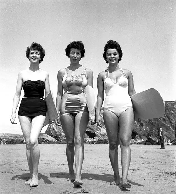 Marilyn Ridge, Lyn Connelly, and Dee Delaney prepare to ride the swell on Newquay beach, Cornwall, 1955. Marilyn Ridge, Lyn Connelly, and Dee Delaney prepare to ride the swell on Newquay beach, Cornwall, 1955.