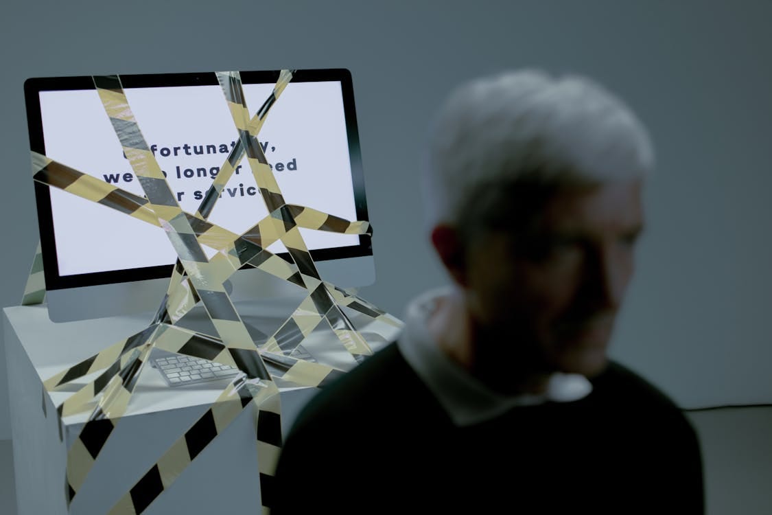 Free A senior man facing the reality of unemployment highlighted by a computer screen and warning tape. Stock Photo Free A senior man facing the reality of unemployment highlighted by a computer screen and warning tape. Stock Photo