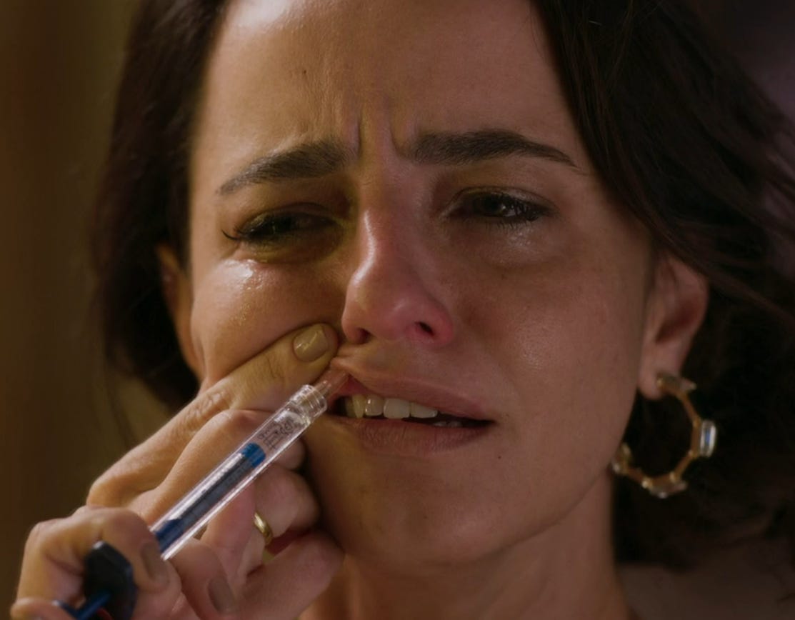 personagem Gisela da novela Beleza Fatal, uma mulher branca, de cabelos castanhos e lisos, enfiando uma agulha no lábio superior