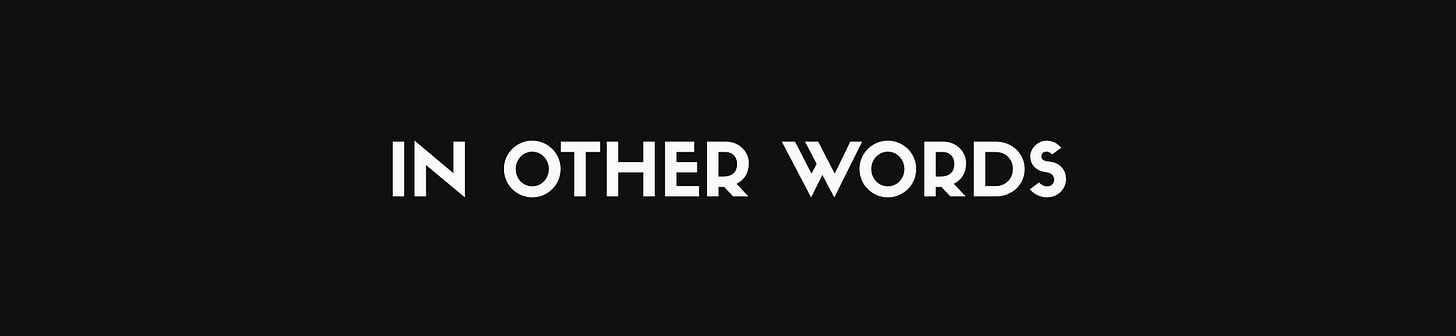 Off-white text reading "IN OTHER WORDS" in a clean, all-caps sans-serif typeface against a near-black background.