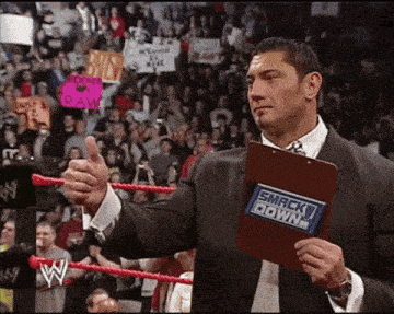 a man in a suit holds a clipboard that says smack down
