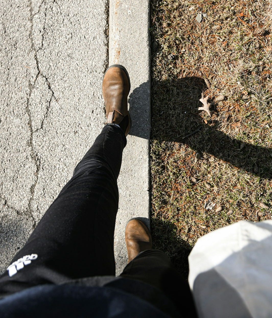 a person standing on a sidewalk with their feet on the ground