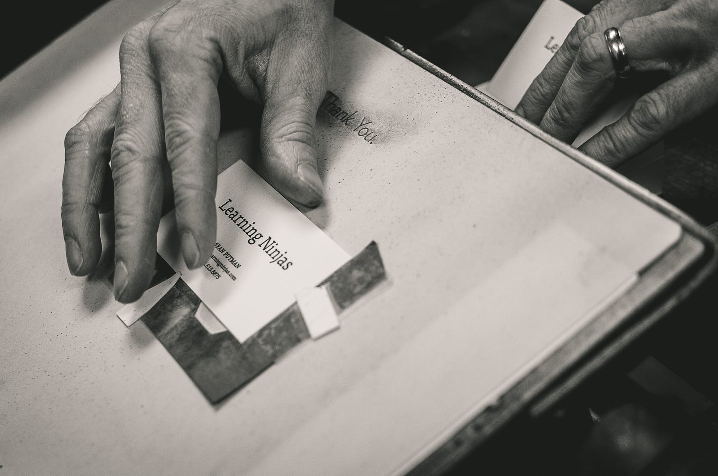 A hand about to withdraw a Learning Ninjas business card from the letterpress plate at Hoban Press.