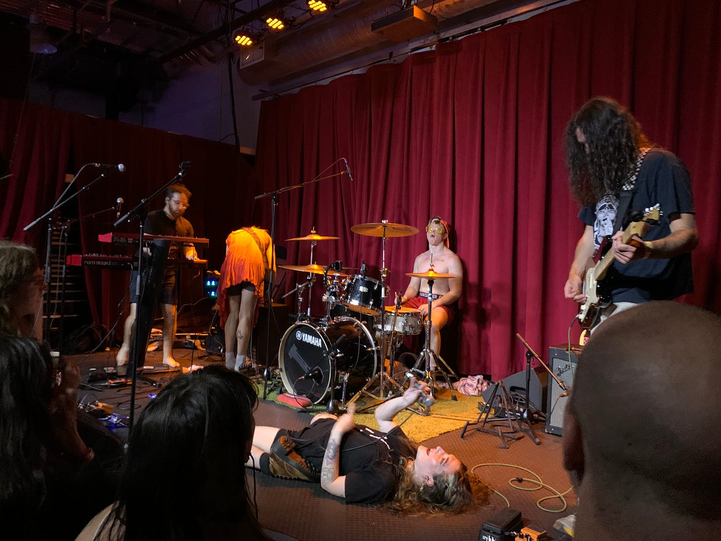 Pretty Bitter performing at Songbyrd Music House. Mel is lying on the stage.