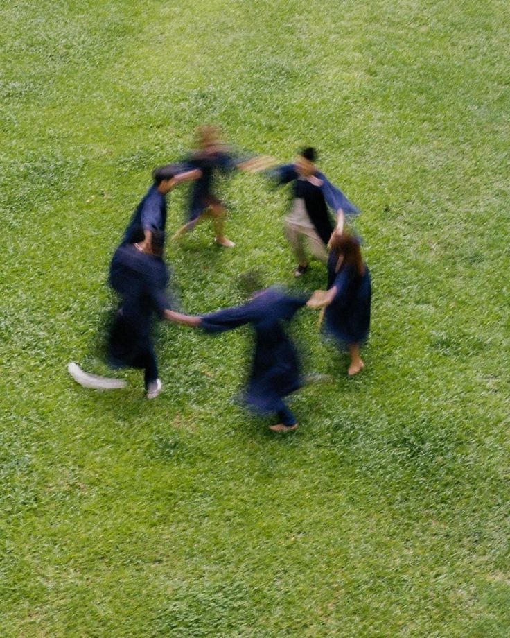 This may contain: a group of people standing in the middle of a circle on top of a grass covered field