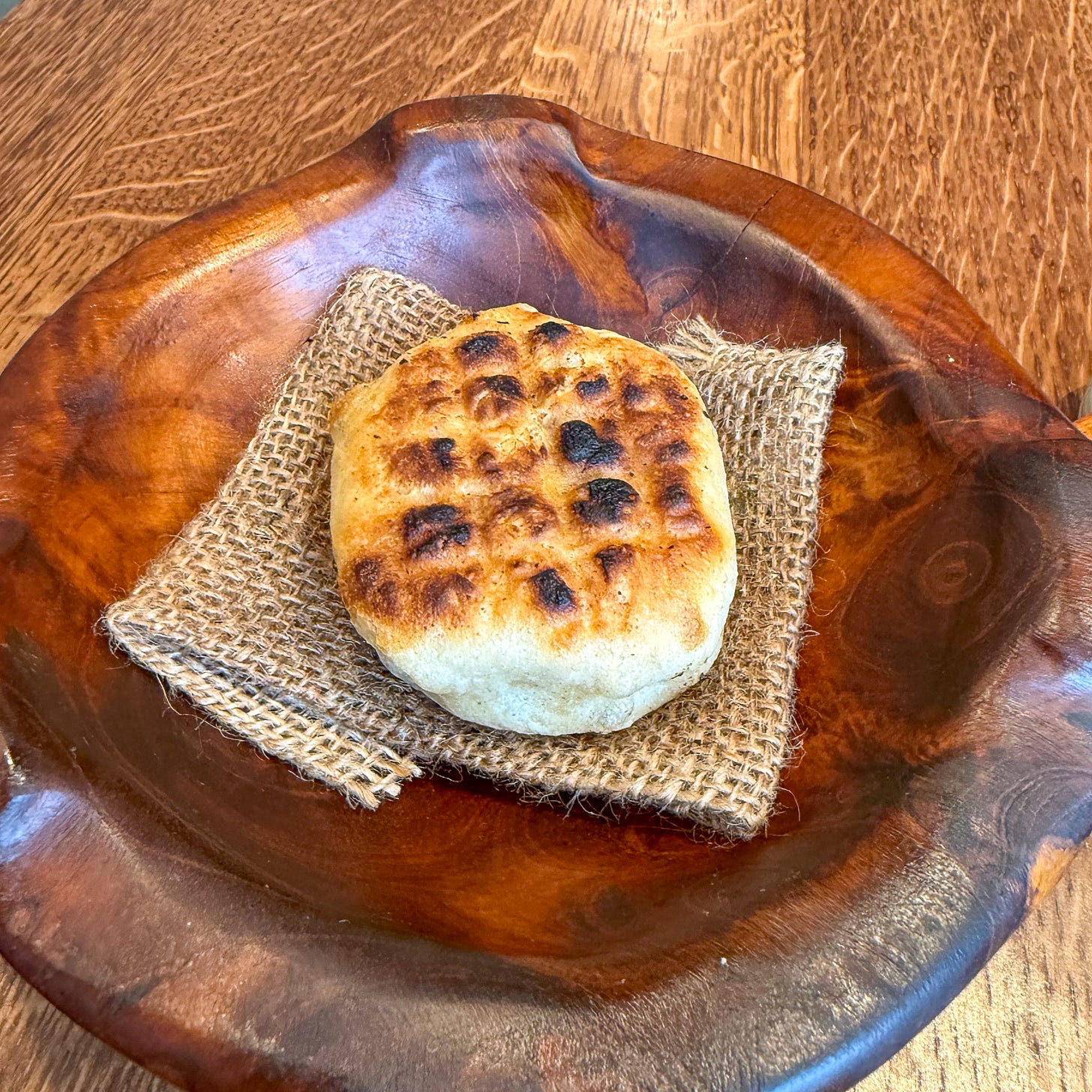 Char-marked pan criollo on burlap in wooden bowl at Eme, Paris 4th