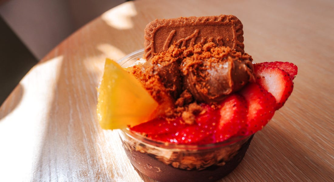 A Biscoff acai bowl with pineapple, strawberries, and banana on top of a wooden table A Biscoff acai bowl with pineapple, strawberries, and banana on top of a wooden table