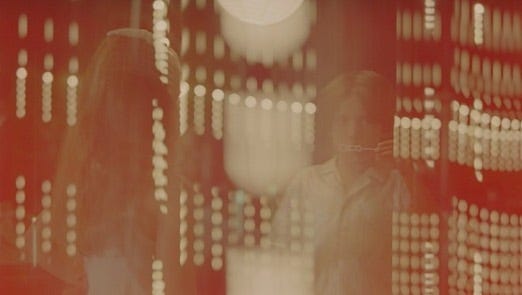 A light leak frame from 35mm film, two children blow bubbles with circular light patterns overlaying in artistic ways