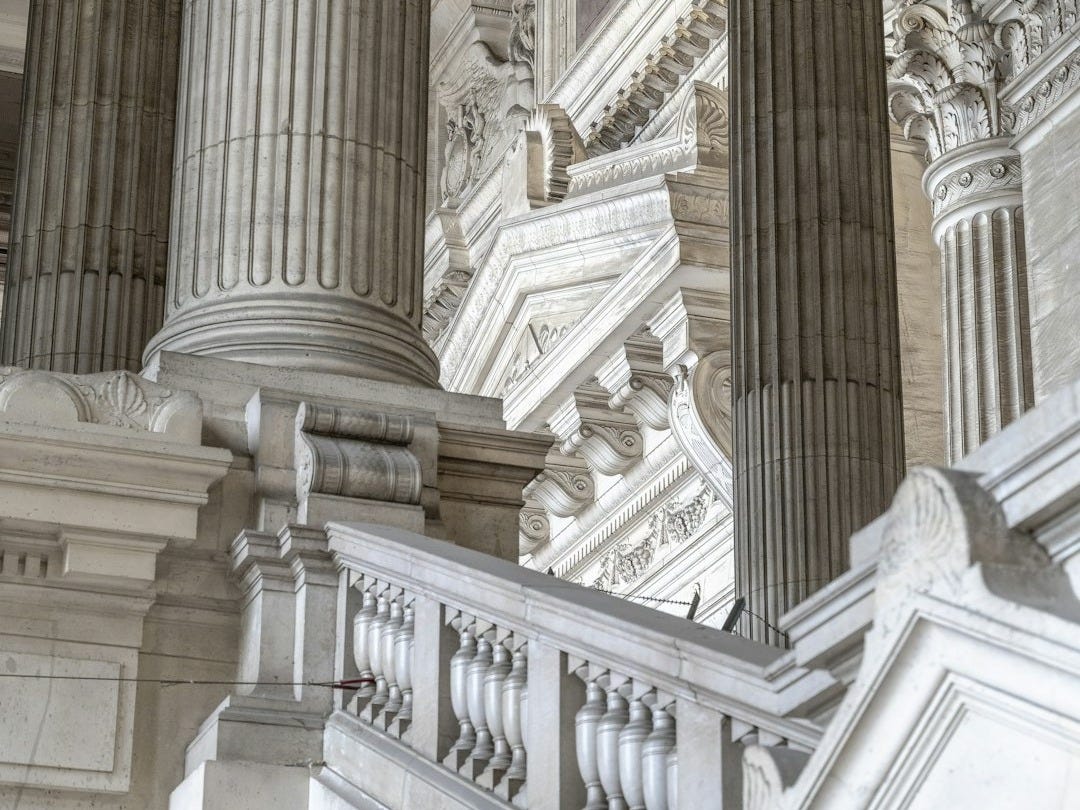 a building with columns and a clock on the side of it a building with columns and a clock on the side of it