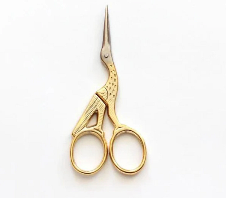 Two pairs of scissors shaped like cranes: one black with blunt tips, and one gold and sharp