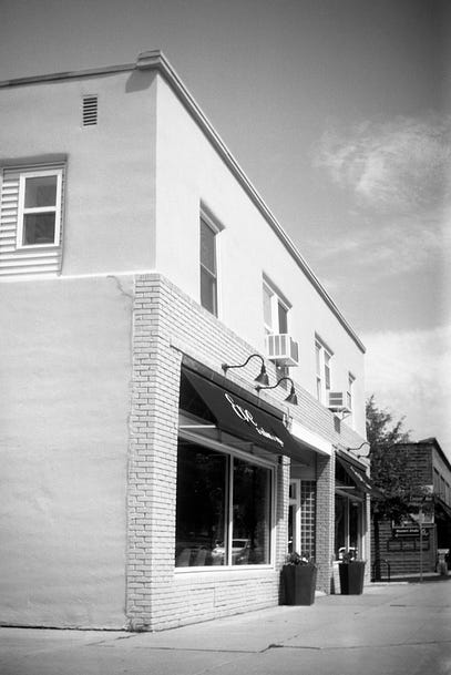 A black and white photograph of a shop with white walls and dark windows
