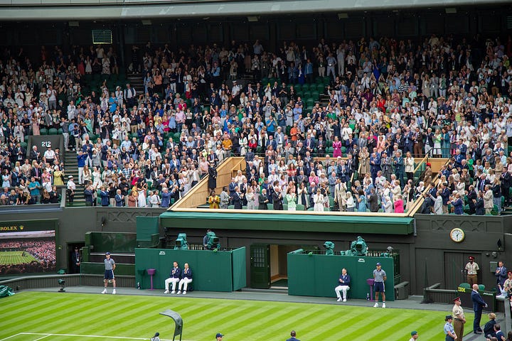 Four scenes from Wimbledon: Ben Shelton serving on an outside court, ball boys and ball girls huddled in Wimbledon uniforms, rain covers pulled across a court showing the Wimbledon crest, and the Royal Box on Centre Court during the Federer ceremony